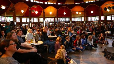 A crowd of people sat inside a Spiegeltent watching a performance at a previous Festival of the Mind