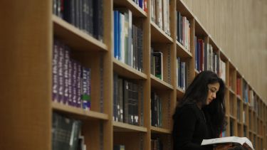 Image of a person reading a book in a library.