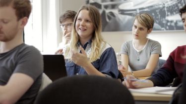 A person with blonde hair talks during a seminar