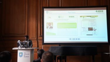 Photograph of Yinka Leo Ogundiran, Chair of the IEEE University of Sheffield Student Branch, speaking about the branch's work at the EMD Symposium