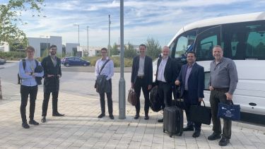 Photograph of delegates at the 2022 EPSRC Future Electrical Machines Manufacturing Hub conference standing next to a minibus