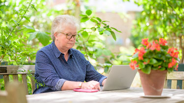 Woman over 50 working on laptop in garden