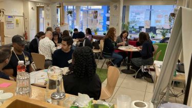 People sat at tables talking to each other in a community centre in Sheffield