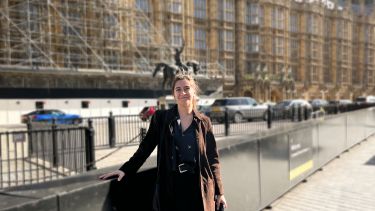Image of Politics graduate Aisha Mahal in front of the houses of parliament after launching a report in parliament