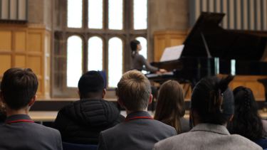 students watching pianist playing on stage 