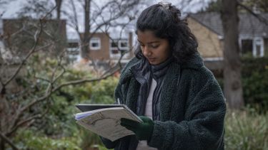 A student making notes in an urban green space