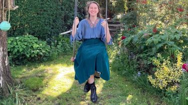 Student on a swing smiling in a garden