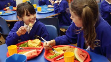 Photograph of two children eating a school meal