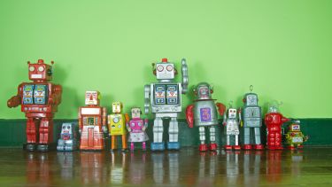 Photograph of toy robots lined up against a green background