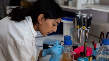 Student in a white lab coat conducting an experiment