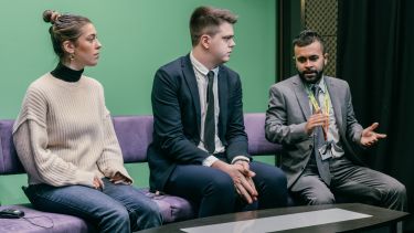 Two men and a woman sat on a couch.