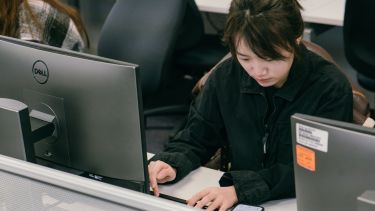 A girl at a computer typing on a keyboard