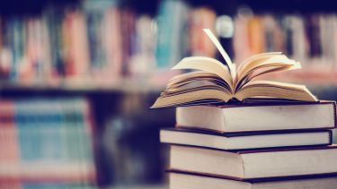 An image of an open book on a table in a library setting.