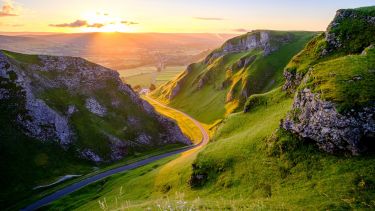 A road winding through the Peak District as the sun rises.