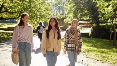 Three students walk through Weston Park on a sunny day