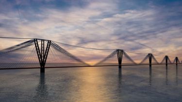 Image of long bridge over river at sunset