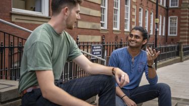 Students Ronak (right) and Alex (left) sit on the steps of the Mappin building