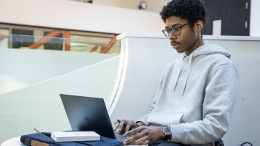 A student sat at a table with his laptop