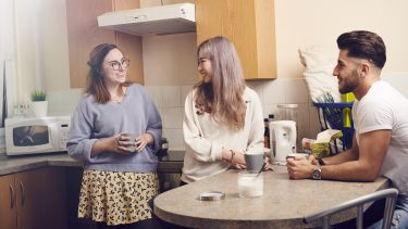 Three students in a shared kitchen.