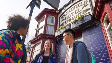 Three students stand and chat outside the Broadfield pub on Abbeydale Road
