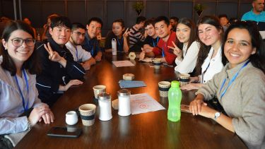 International students sitting around a cafe table and smiling