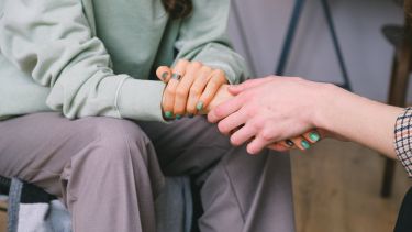 Two people holding hands in comfort.