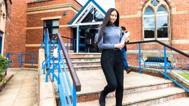 Postgraduate Student walking down the steps of Bartolome House