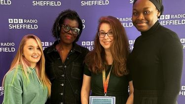 A group of four women stand smiling in front of a backdrop that reads 'BBC Radio Sheffield'