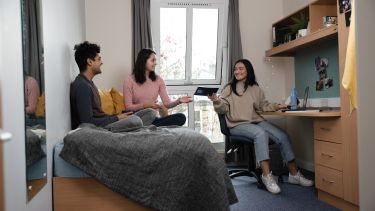 Three students hanging out in an accommodation bedroom 