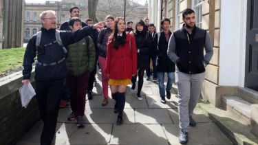 A group of international students being shown a local sight while walking down a pavement