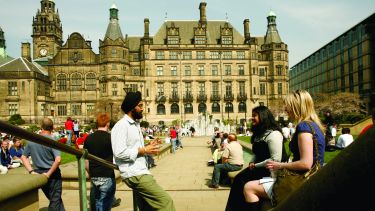 Three students having a conversation by the Peace Gardens and Sheffield Town Hall