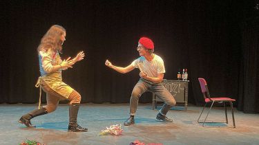 Two student actors in a pretend fight in the French play. One wearing a red baret