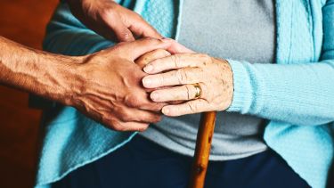 A carer holding the hand of an elderly woman