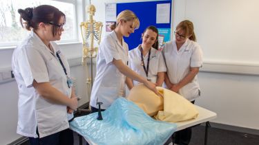 A photo of four student midwives practising their clinical skills.