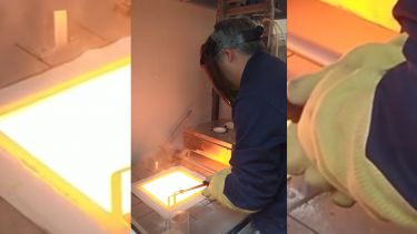 Photo of someone melting glass in a hot forge