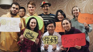 Group of students hold up signs saying hello in different languages