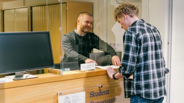Dan Hector helping a student at the enquiry desk.