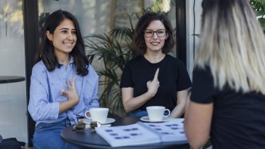 Photograph of 3 women communicating via sign language