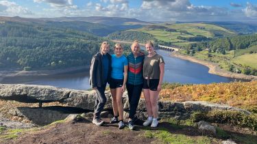 Four young women standing on hill side in Peak district with Lady Bower in the background