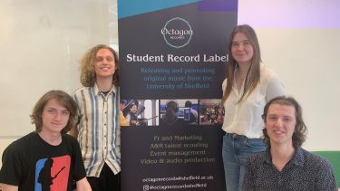 group of students standing in front of record label banner