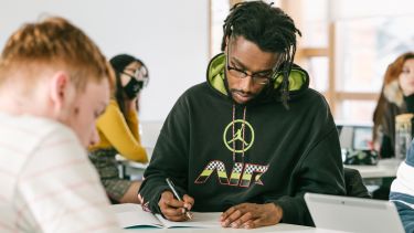 Student at desk writing in notebook 