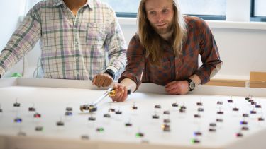 Two academics arranging Kilobots on a plain surface