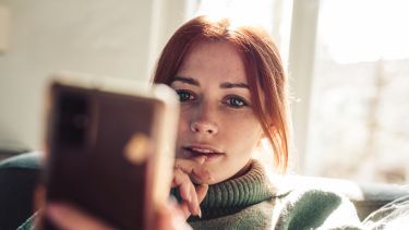 Photo of a young woman looking at a phone screen