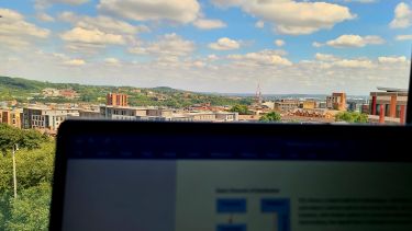 A laptop with the Sheffield skyline out of the window.