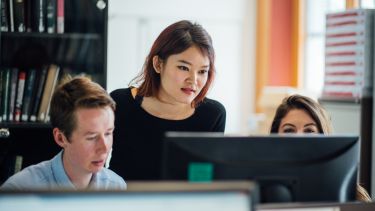 Three students looking at a computer screen