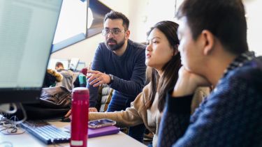 Academic with two students by a computer