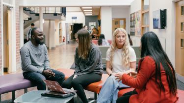 Photo of postgraduate Law students chatting in the Bartolomé House atrium