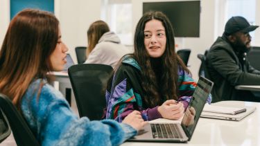 Two postgraduate students working together in a seminar room in Bartolomé House