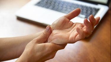 A lady holding her hands while suffering from pain