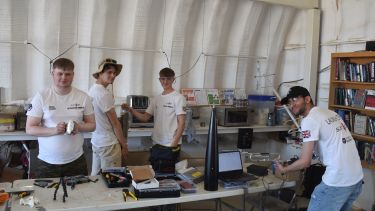 Photograph of team members setting up the radio link between ground station and rocket flight computer before rocket integration